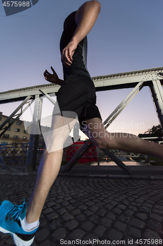 Image of man jogging across the bridge in the city