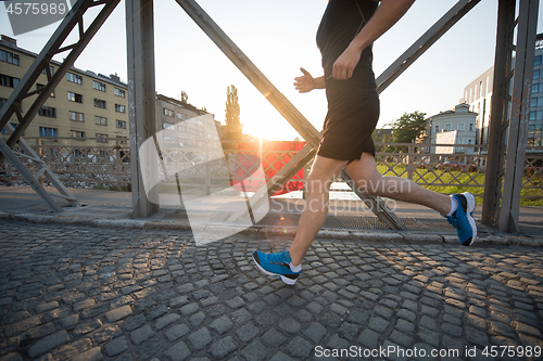 Image of man jogging across the bridge at sunny morning