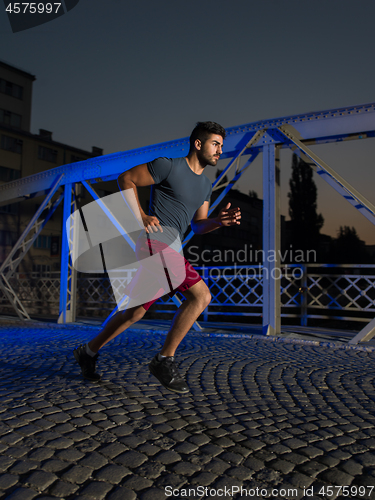 Image of man jogging across the bridge in the city