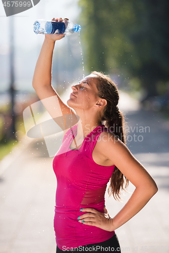 Image of woman pouring water from bottle on her head