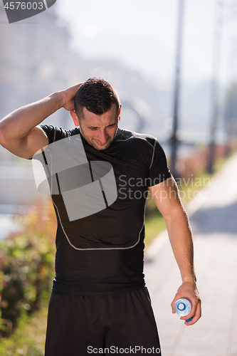 Image of man pouring water from bottle on his head