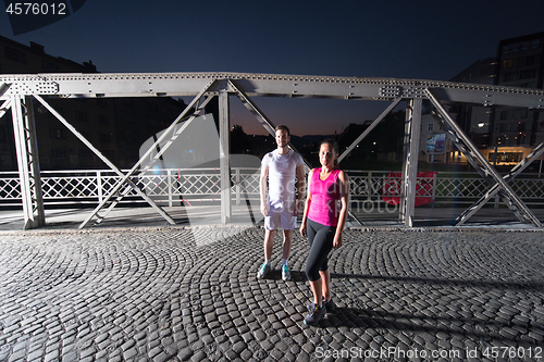 Image of couple jogging across the bridge in the city