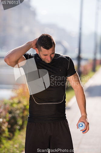 Image of man pouring water from bottle on his head