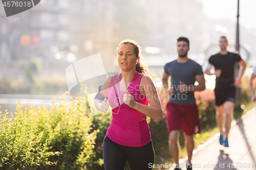 Image of group of young people jogging in the city