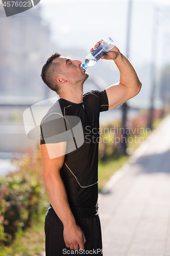 Image of man drinking water from a bottle after jogging