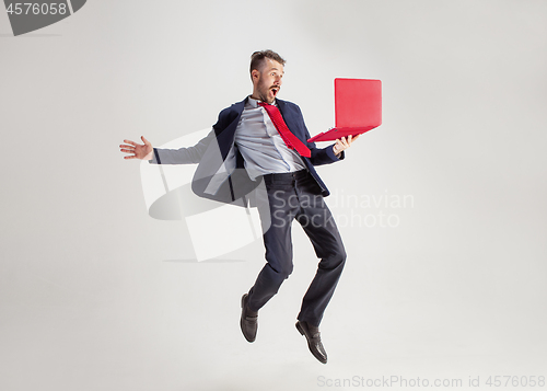Image of Image of young man over white background using laptop computer while jumping.
