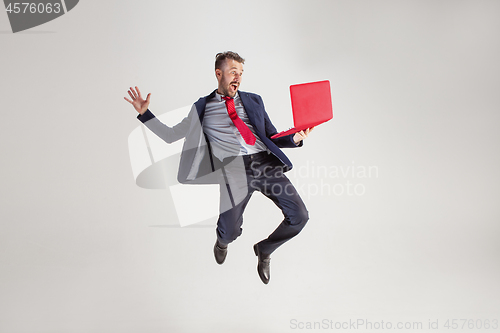 Image of Image of young man over white background using laptop computer while jumping.