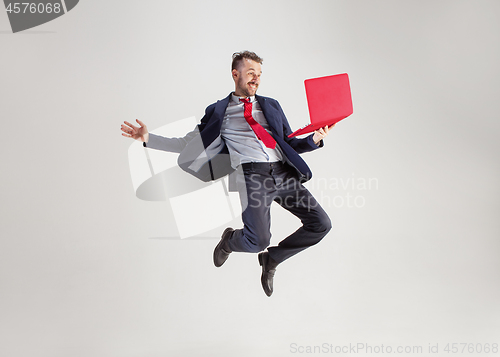 Image of Image of young man over white background using laptop computer while jumping.