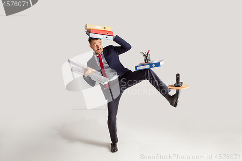 Image of Young businessman in a suit juggling with office supplies in his office, isolated on white background