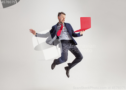 Image of Image of young man over white background using laptop computer while jumping.