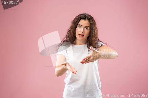 Image of Beautiful female half-length portrait isolated on pink studio backgroud. The young emotional surprised woman