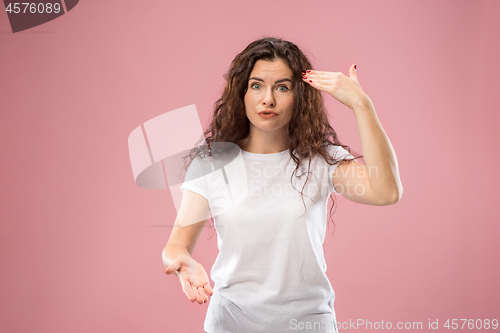 Image of Beautiful female half-length portrait isolated on pink studio backgroud. The young emotional surprised woman