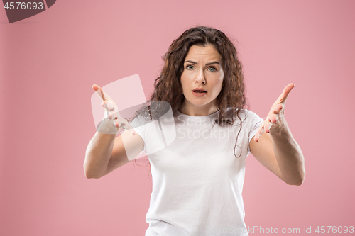 Image of Beautiful female half-length portrait isolated on pink studio backgroud. The young emotional surprised woman