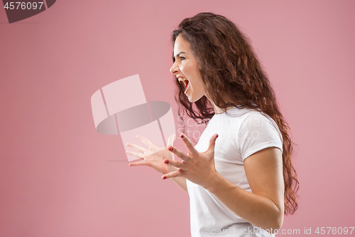 Image of The young emotional angry woman screaming on pink studio background