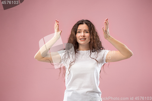 Image of Beautiful female half-length portrait isolated on pink studio backgroud. The young emotional surprised woman