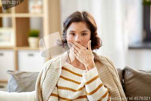 Image of sick woman in blanket coughing at home