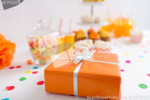 Image of birthday present in orange wrap on table at party