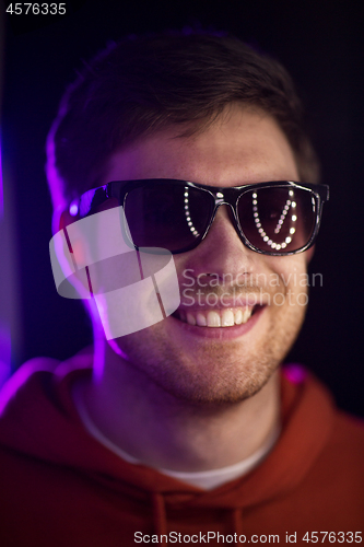 Image of man in sunglasses over ultra violet neon lights