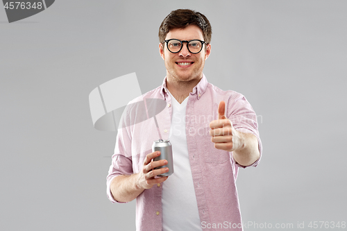 Image of happy man with soda in tin can showing thumbs up