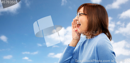 Image of senior woman in glasses calling over sky