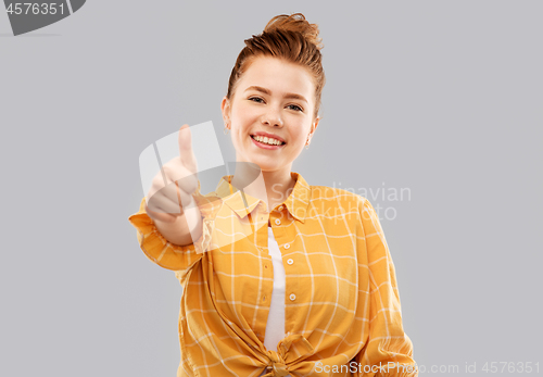 Image of smiling red haired teenage girl showing thumbs up