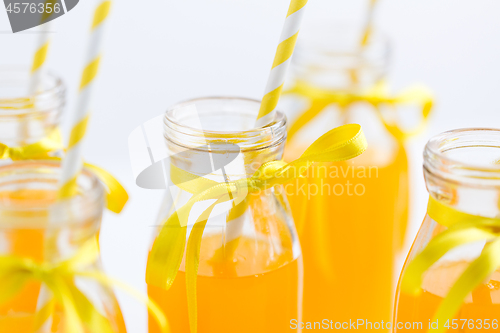 Image of orange juice in glass bottles with paper straws