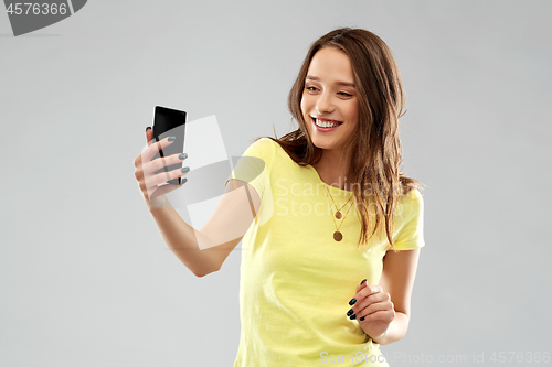 Image of smiling teenage girl taking selfie by smartphone