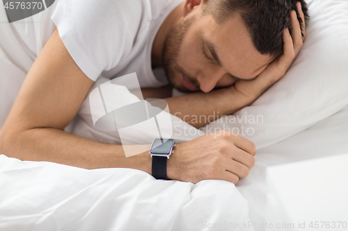 Image of close up of man with smart watch sleeping in bed