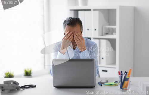 Image of stressed businessman with laptop working at office