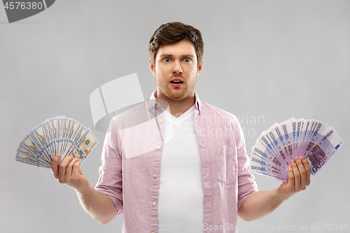 Image of confused young man with euro and dollar money