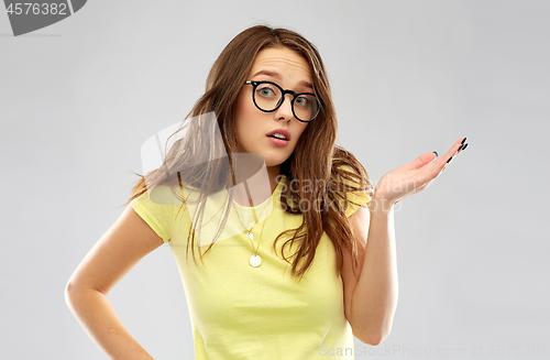 Image of young woman or teenage girl in glasses shrugging