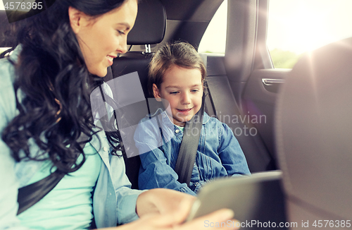 Image of happy family with tablet pc driving in car