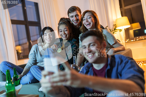 Image of friends with smartphone and drinks at night home