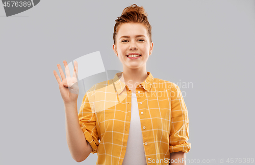 Image of red haired teenage girl showing four fingers