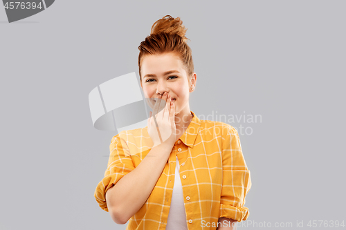 Image of confused red teenage girl covering mouth by hand