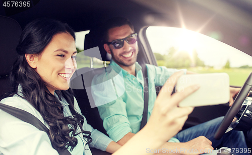 Image of happy couple in car taking selfie with smartphone