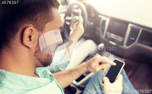 Image of man and woman with smartphones driving in car