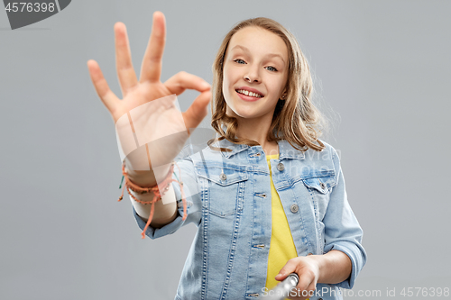 Image of teenage girl taking picture by selfie stick