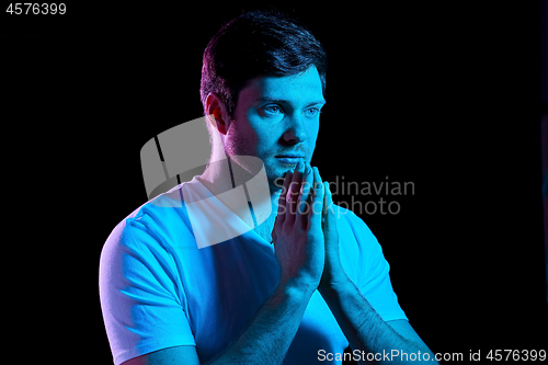 Image of man praying god over ultra violet neon lights