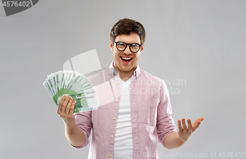 Image of happy young man in glasses with fan of euro money