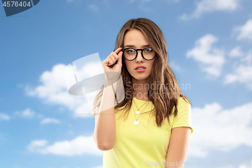 Image of young woman or teenage girl in glasses over sky