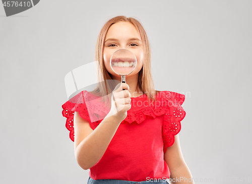 Image of happy girl with magnifying glass over her teeth