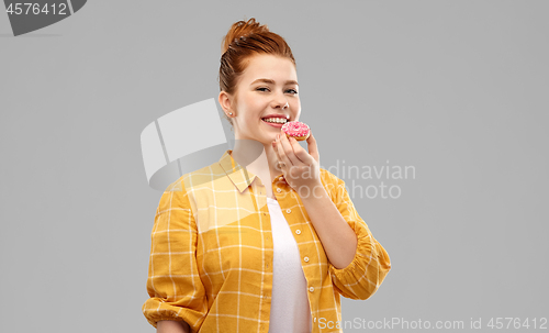 Image of smiling red haired teenage girl eating donut