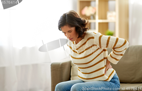 Image of unhappy woman suffering from backache at home