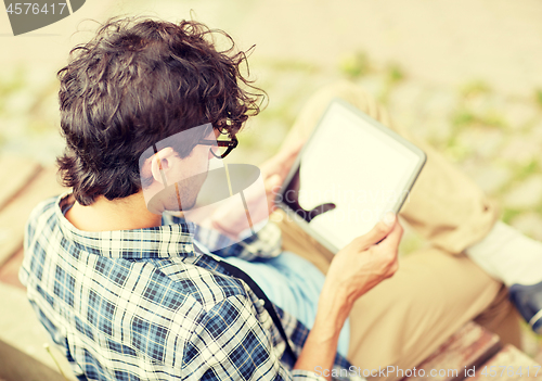 Image of man with tablet pc sitting on city street bench