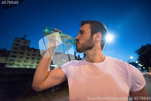 Image of man drinking water after running session