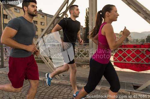 Image of group of young people jogging across the bridge