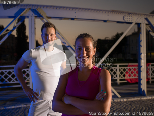 Image of portrait of couple jogging across the bridge in the city