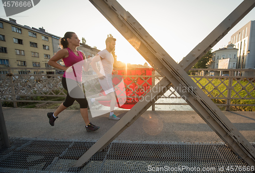 Image of young couple jogging across the bridge in the city