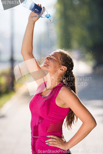 Image of woman pouring water from bottle on her head